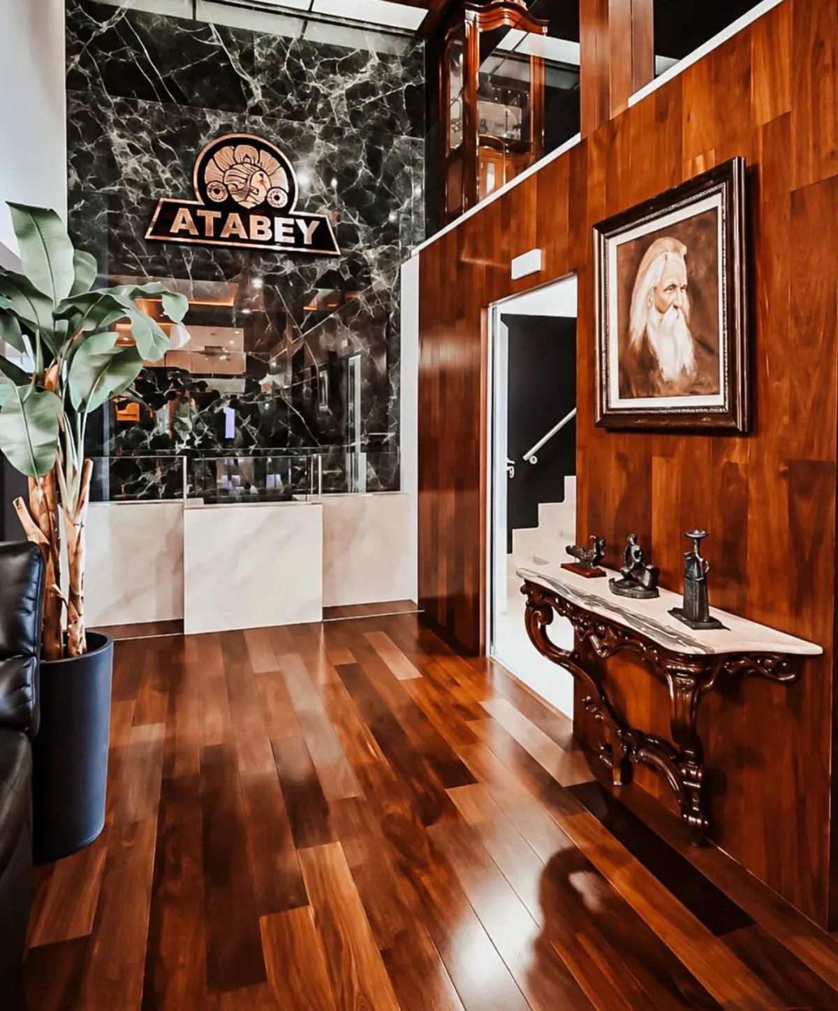 Wood-paneled lounge with an illuminated Atabey sign, a framed portrait and an ornate console table inside Selected Tobacco's Madrid facility